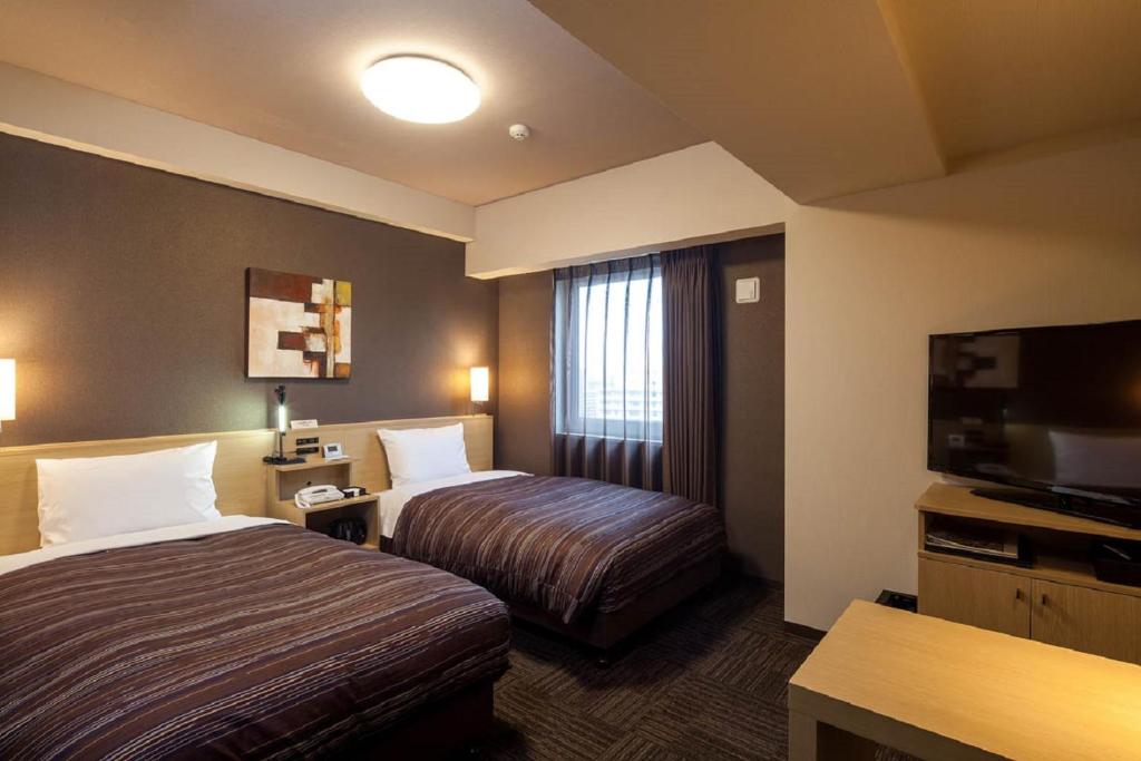 Habitación de hotel con 2 camas y TV de pantalla plana. en Hotel Route-Inn Higashihiroshima Saijo Ekimae en Higashihiroshima
