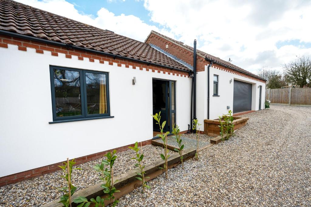 a white house with a gravel driveway at LITTLE HOUSE - Perfect for exploring The Broads in Acle
