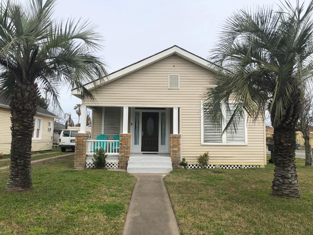 a house with two palm trees in front of it at Seaside Cottage in Galveston