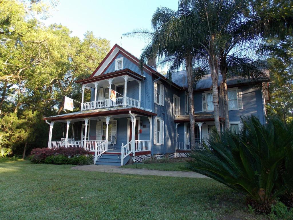 una casa azul con un porche y una palmera en The Ann Stevens House, en Cassadaga