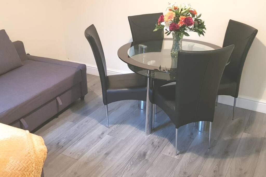 una mesa y sillas con un jarrón de flores. en Homely Experience for Contractors,Grays en Grays Thurrock