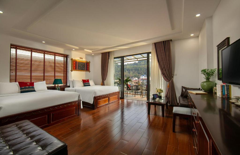 a hotel room with two beds and a television at Sapa Mountain Queen House in Sa Pa