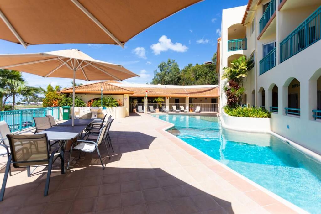 a table with chairs and an umbrella next to a swimming pool at Tropical Oasis, Million Dollar Views, 2 Pools in Cannonvale