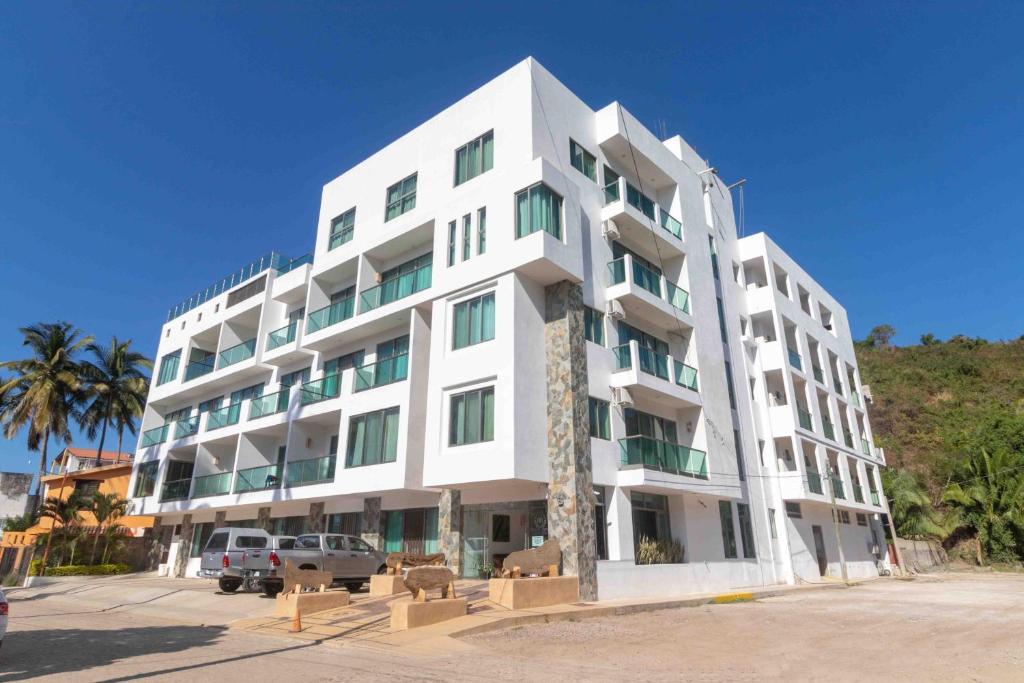 ein weißes Gebäude mit einer Palme davor in der Unterkunft Rincon Resort in Los Ayala