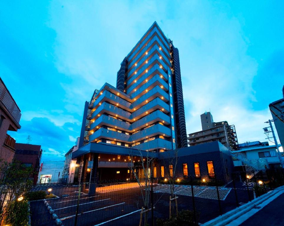HOTEL ROUTE-INN Osaka Takaishi Hagoromo Ekimae في Takaishi: مبنى طويل في مدينة في الليل