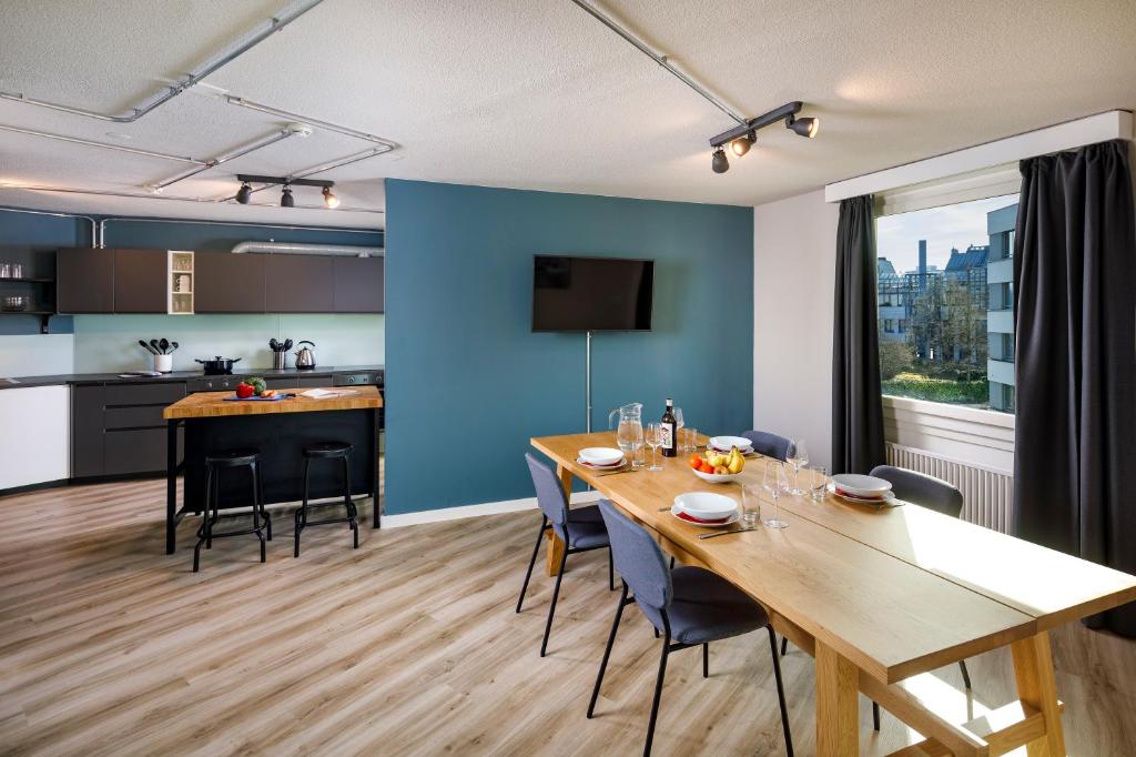 a kitchen with a table, chairs and a refrigerator at Hotel Welcome Inn in Kloten