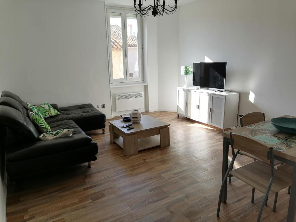 ein Wohnzimmer mit einem Sofa, einem Tisch und einem TV in der Unterkunft T3 proche de la mer in Portel-des-Corbières