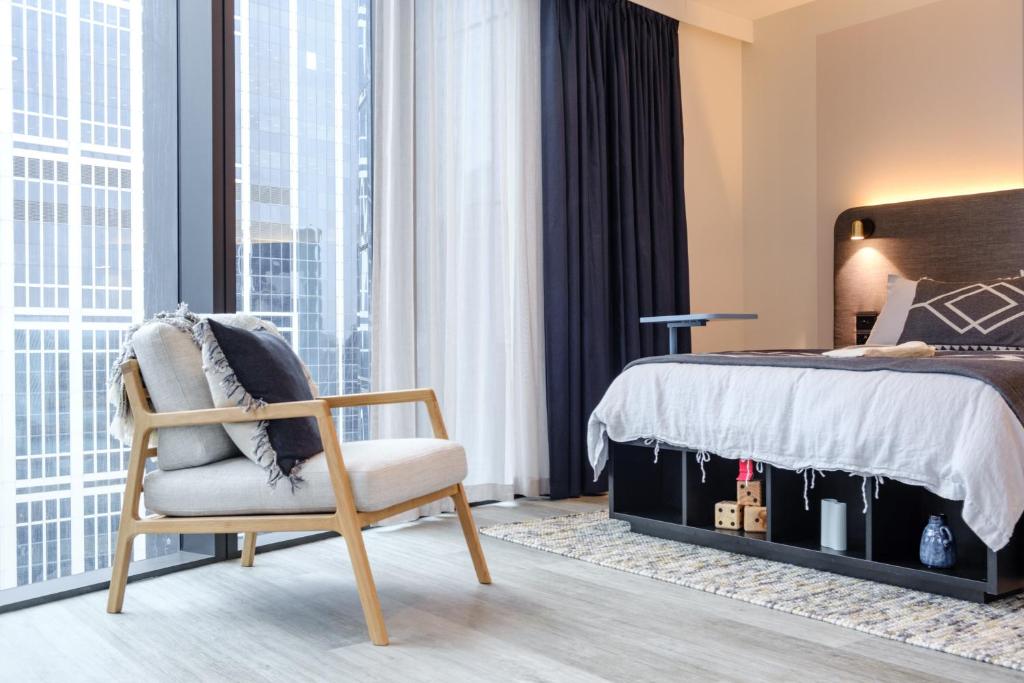 - une chambre avec un lit, une chaise et des fenêtres dans l'établissement Scape Living at Aurora, à Melbourne