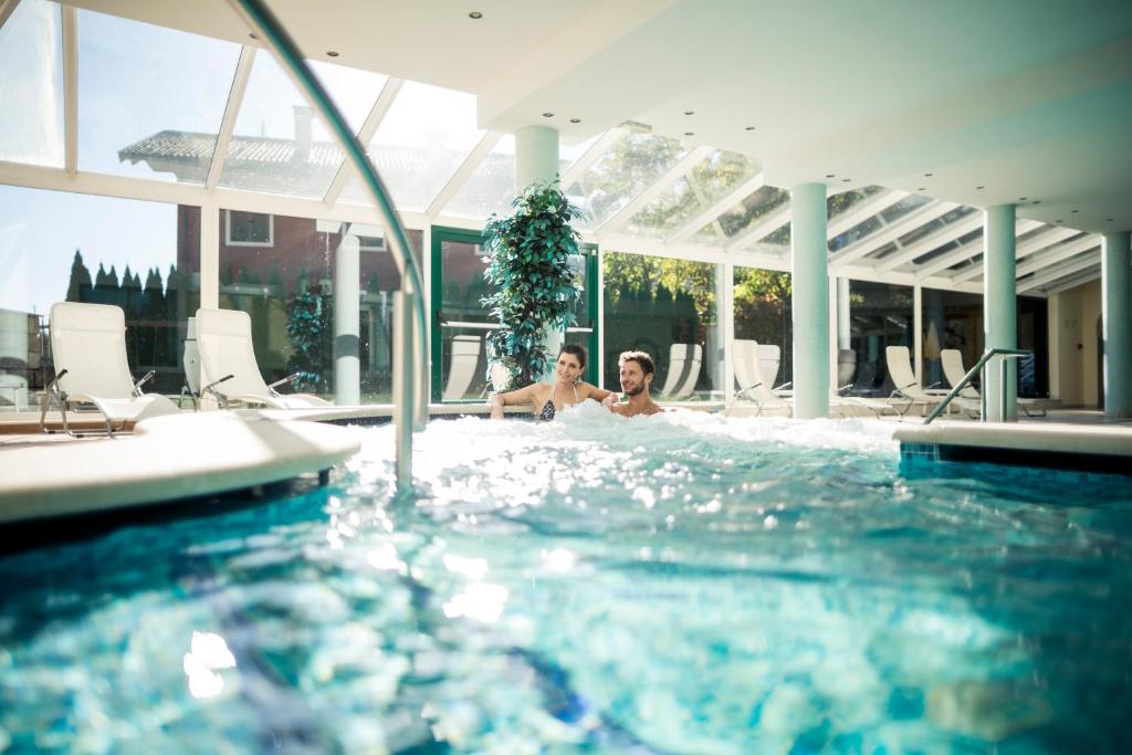 dos personas sentadas en una piscina en Hotel Jager Hans, en San Martino