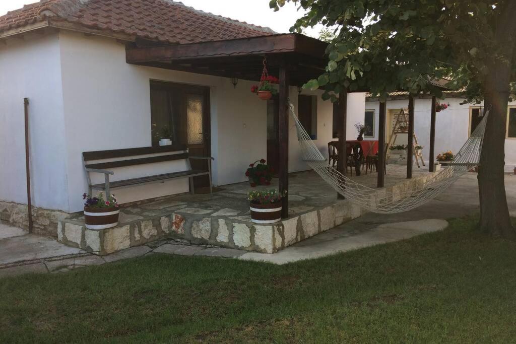 une terrasse couverte avec un hamac et une maison dans l'établissement Guest House Kostadinovi, à Balgarevo