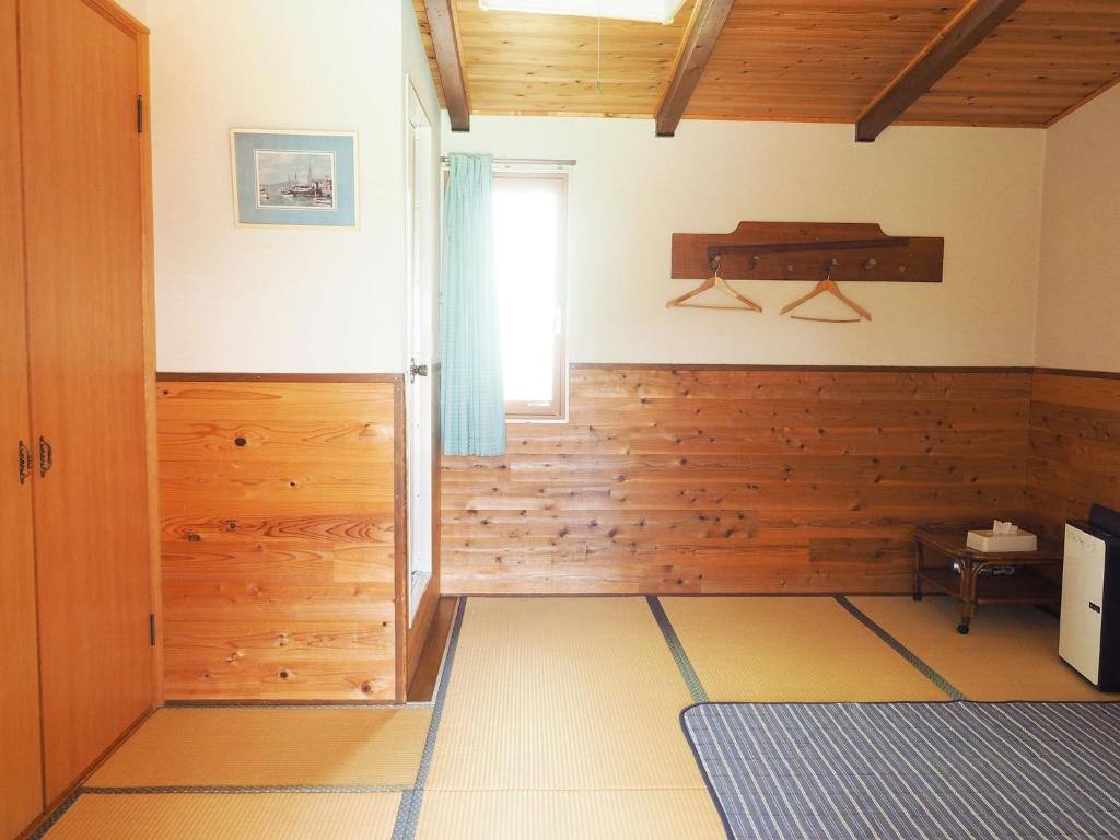Habitación con paredes revestidas de madera y ventana. en olive no sato vingh four eyes shodoshima / Vacation STAY 79069, en Kusakabe