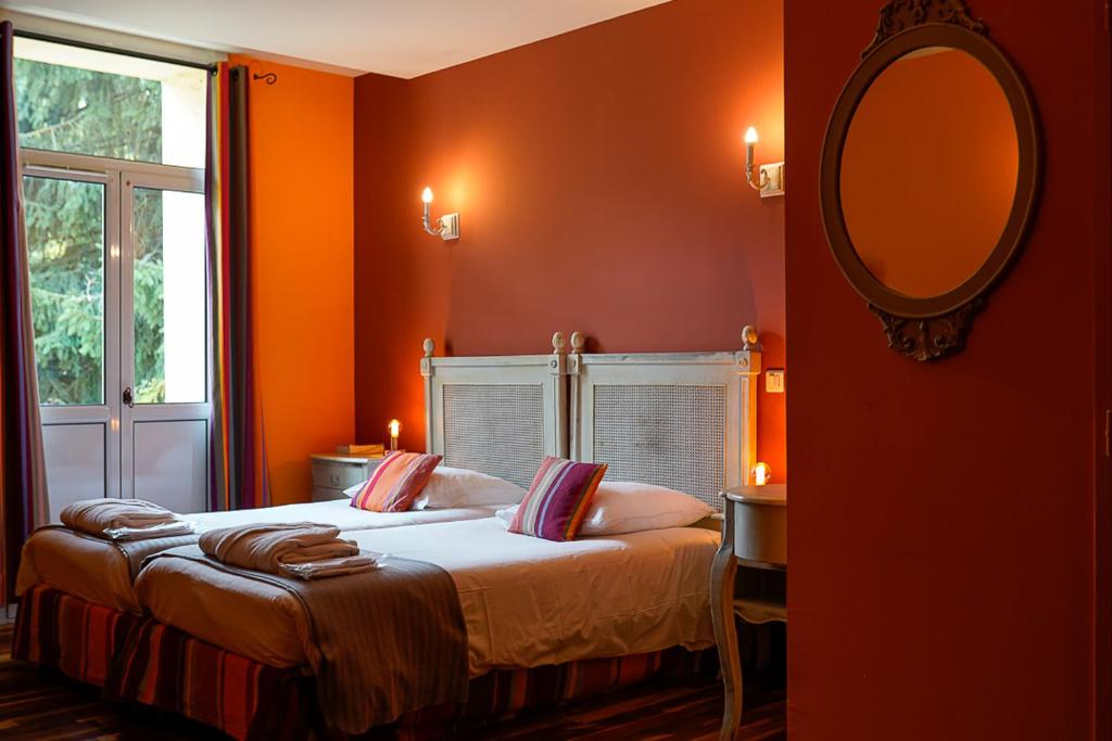 a bedroom with orange walls and a bed with a mirror at Auberge du Manet in Montigny-le-Bretonneux