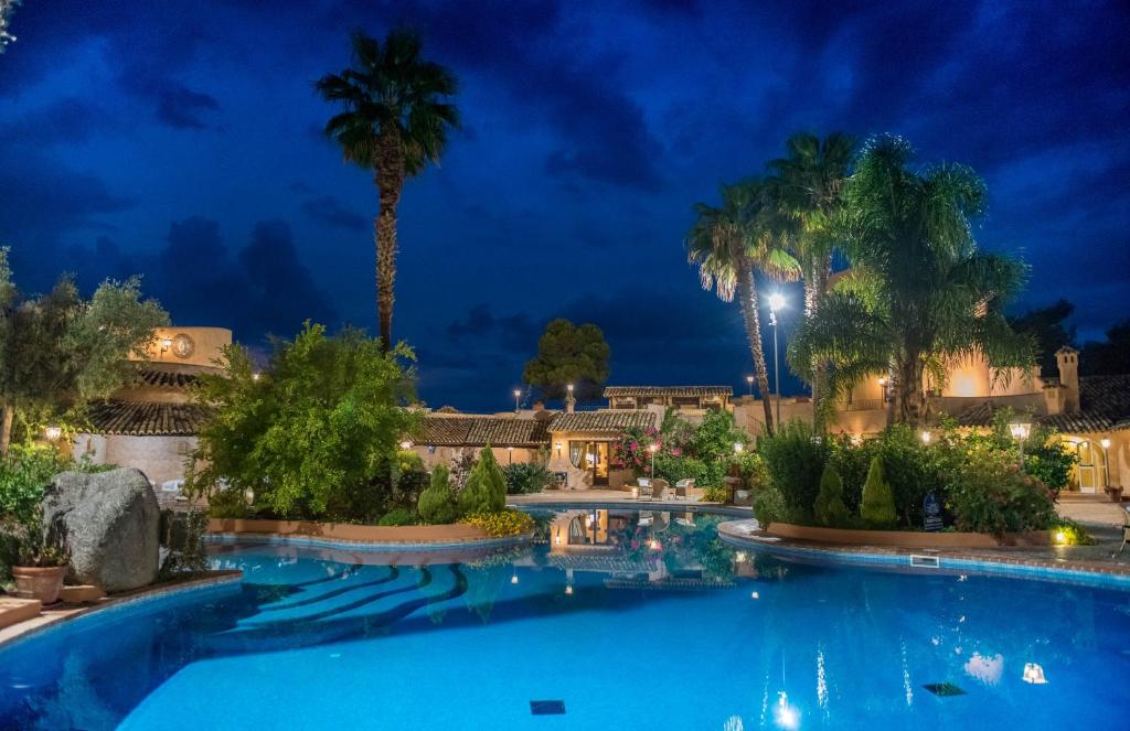 a swimming pool at night with palm trees at Hotel Porto Pirgos in Parghelia