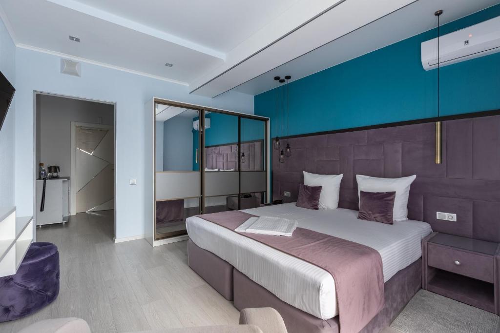 a bedroom with a large bed and a blue wall at Hotel Vogue in Anapa