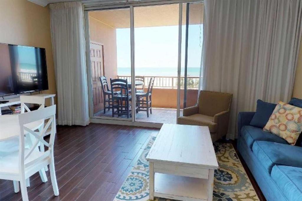 sala de estar con sofá azul, mesa y balcón en The Beach Club Resort and Spa V, en Gulf Highlands