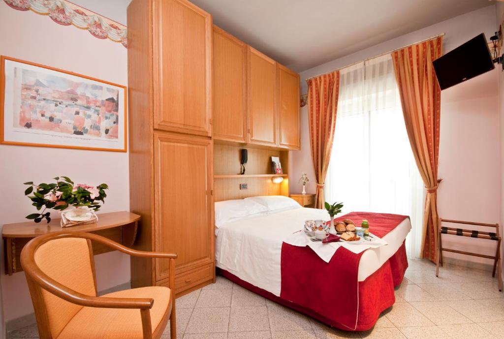 a hotel room with a bed with a table and a chair at Hotel Kennedy in Rimini