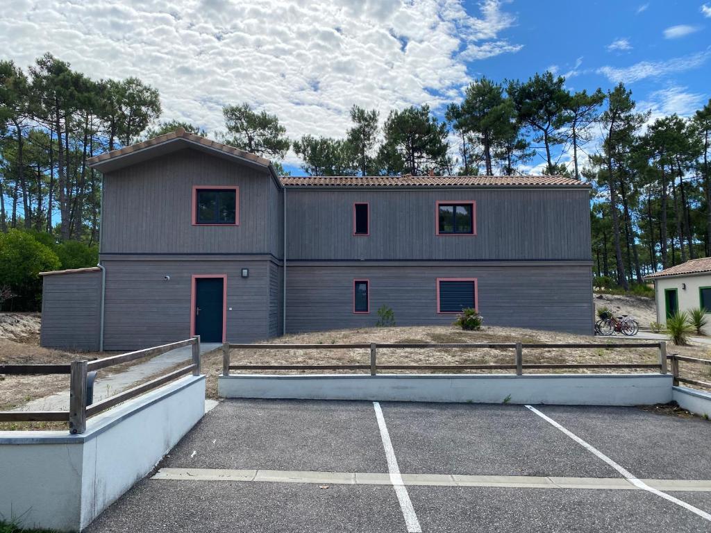 un grand bâtiment gris avec un parking dans l'établissement Villa Marie, à Lacanau