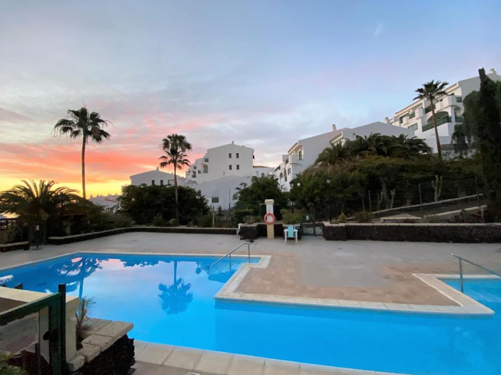 ein großer Pool mit Sonnenuntergang im Hintergrund in der Unterkunft BuenaVista Apartment in Windsor Park in Adeje