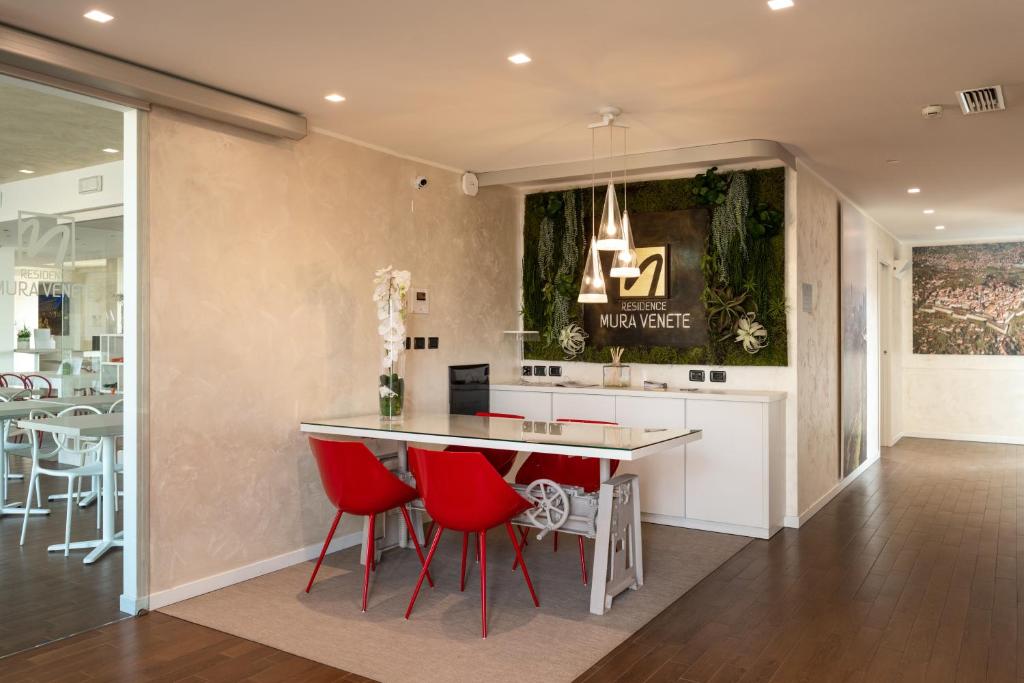 una cucina con sedie rosse e un tavolo in una stanza di Residence Mura Venete a Ponte San Pietro