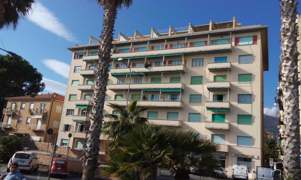 a tall building with palm trees in front of it at Piazza Mazzini 21 in Loano