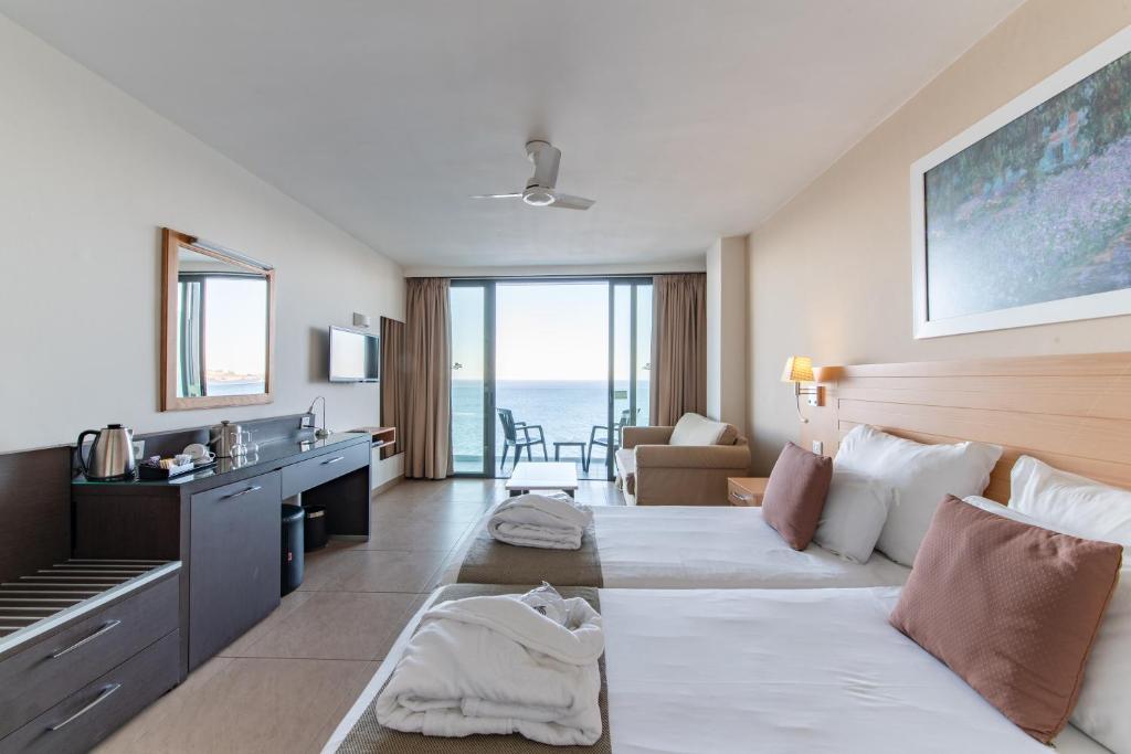 a hotel room with a bed and a view of the ocean at The Preluna Hotel in Sliema