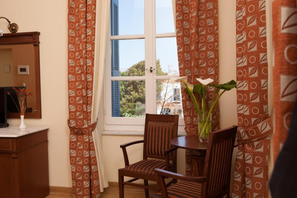 a dining room with a table and two chairs and a window at Egli Hotel in Andros