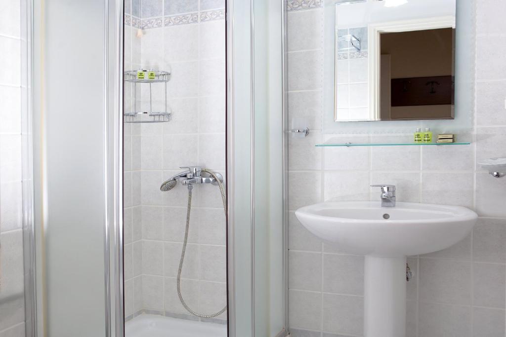 a white bathroom with a sink and a shower at Egli Hotel in Andros