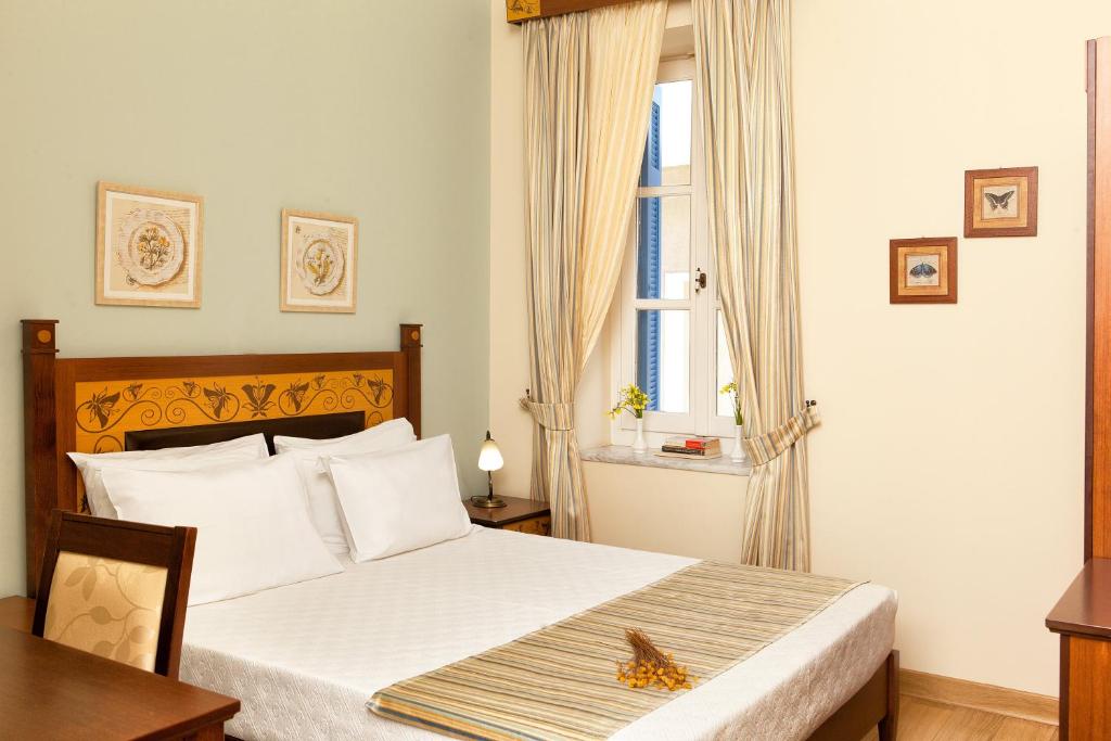 a bedroom with a bed with a table and a window at Egli Hotel in Andros
