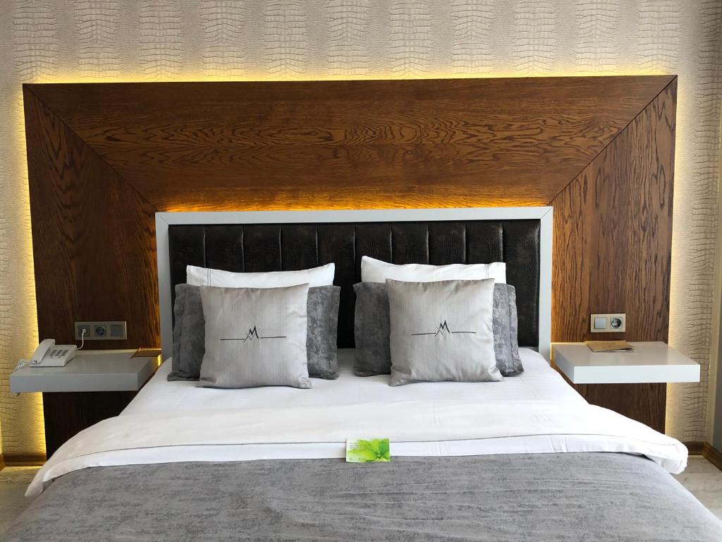 uma cama grande com uma cabeceira em madeira e almofadas brancas em Maison Vourla Hotel em Urla