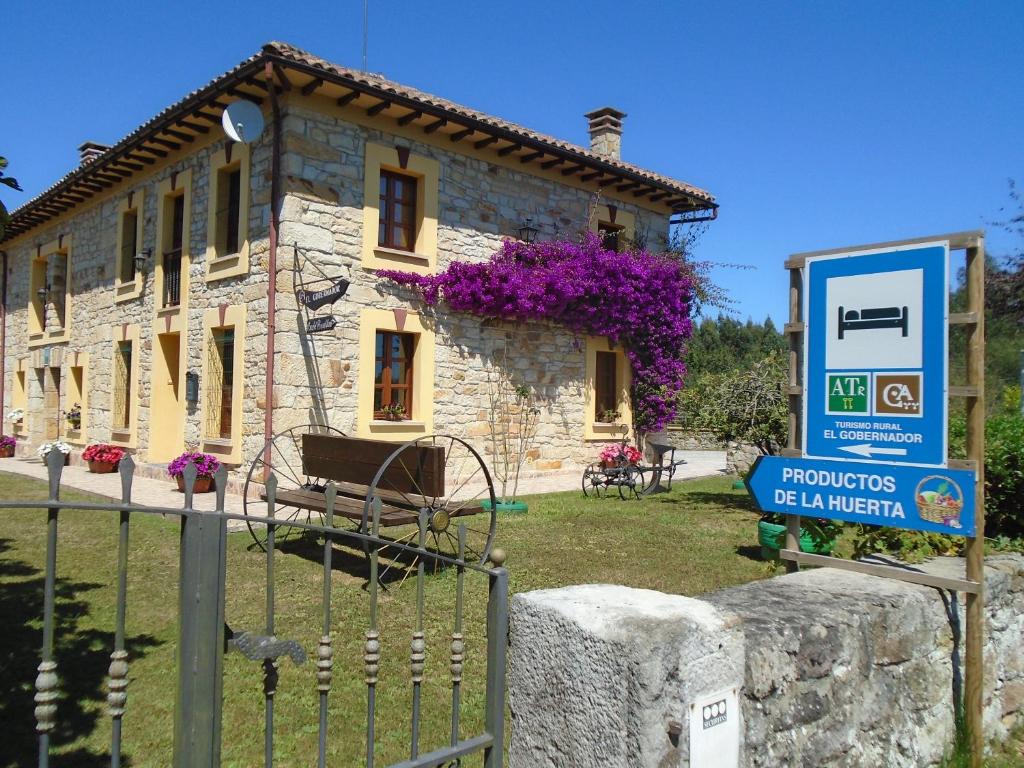 una casa de piedra con un cartel delante en Apartamentos Rurales El Gobernador, en Villaviciosa