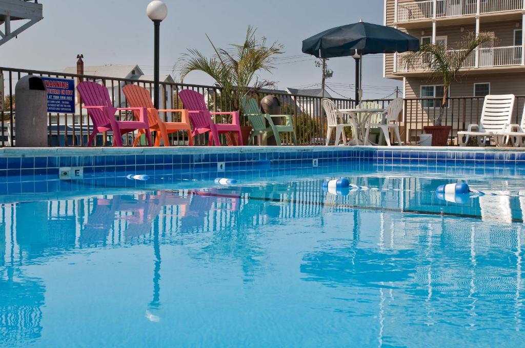 a swimming pool with colorful chairs and an umbrella at Rideau Oceanfront Motel in Ocean City
