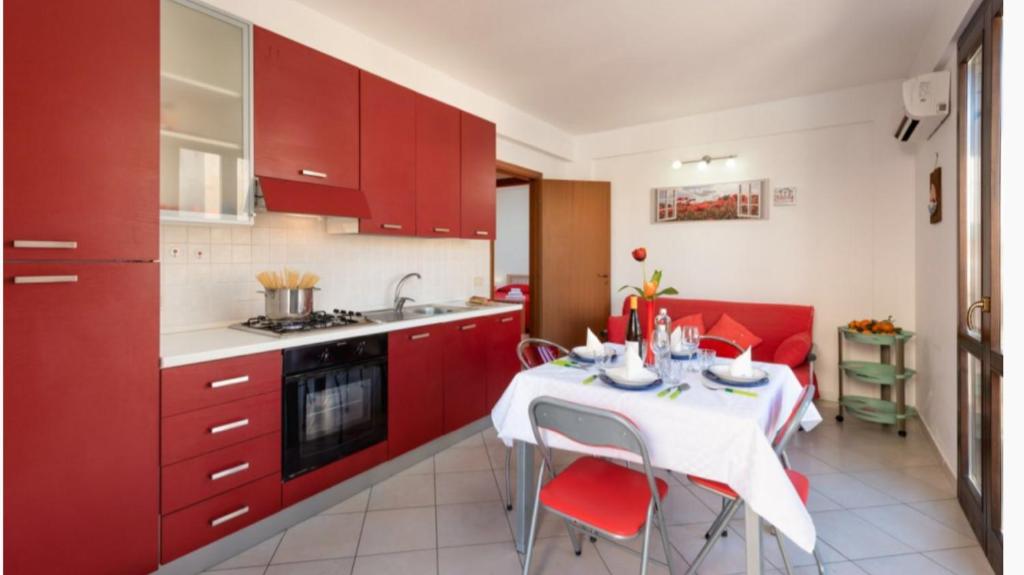 a kitchen with red cabinets and a table with red chairs at Hibiscus in San Vito lo Capo