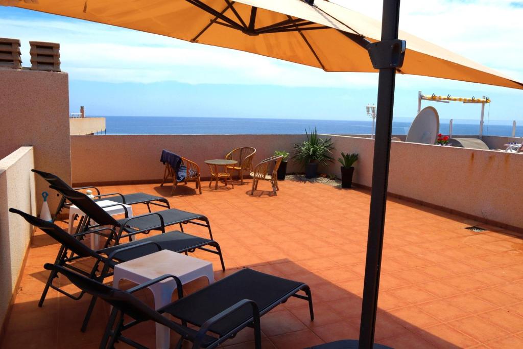 a patio with chairs and tables and an umbrella at 2 bed penthouse, Bolnuevo in Bolnuevo