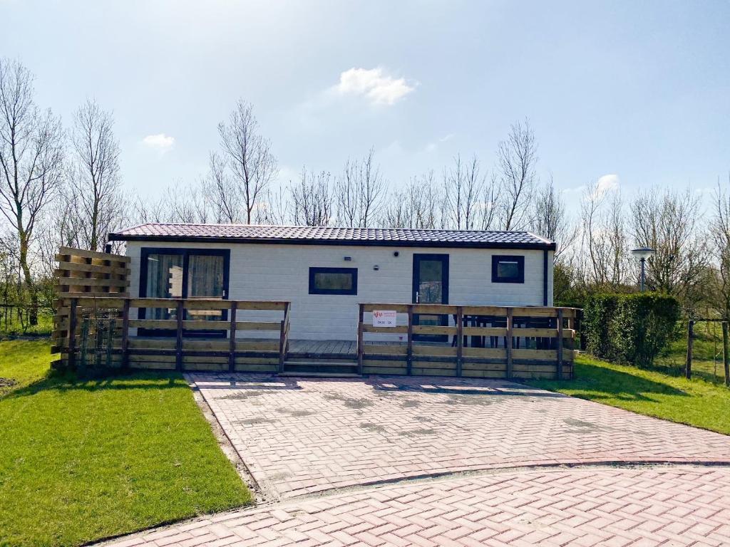 uma pequena casa branca com uma cerca em frente em Familie Chalet Oostkapelle OK30 em Oostkapelle