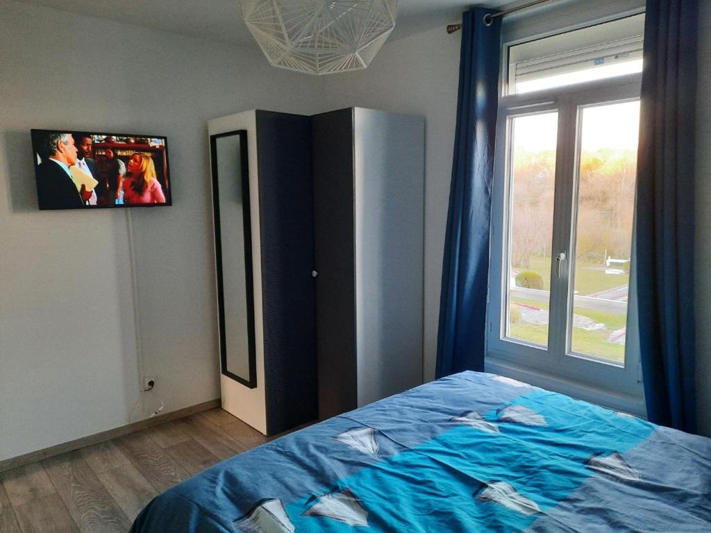 a bedroom with a bed and a tv on the wall at La Tanatte de wimereux sur la côte d opale in Wimereux
