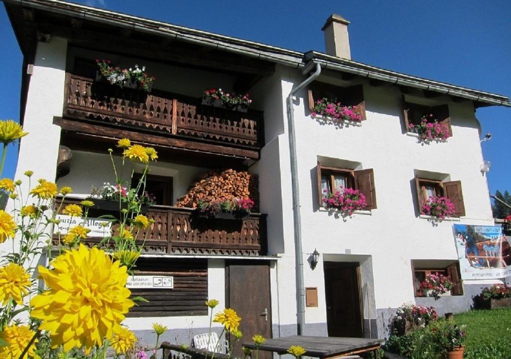 una casa blanca con flores en los balcones en Fuldera Daint / chasa Zanoli, en Fuldera