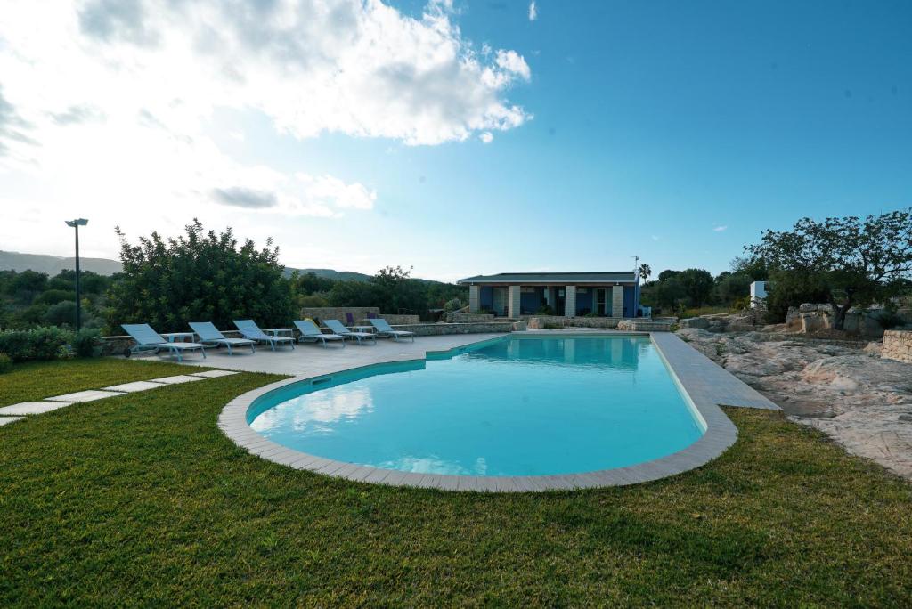 a swimming pool with chairs and a house at Le Cave di Fontane Bianche in Cassibile