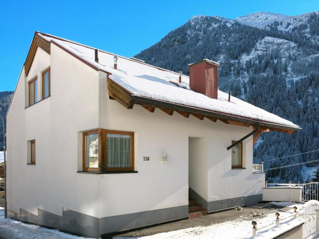a white house with mountains in the background at Apartment Niederhof by Interhome in Kappl