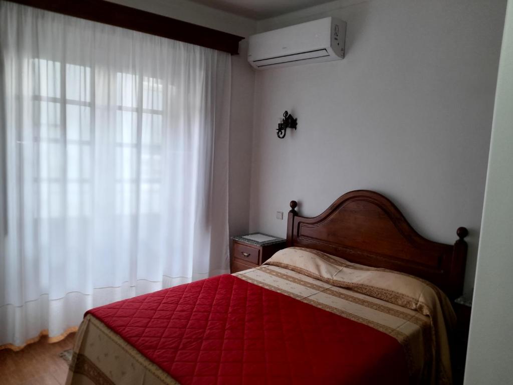 1 dormitorio con 1 cama con manta roja y ventana en Residencial das Trinas 2, en Guimarães