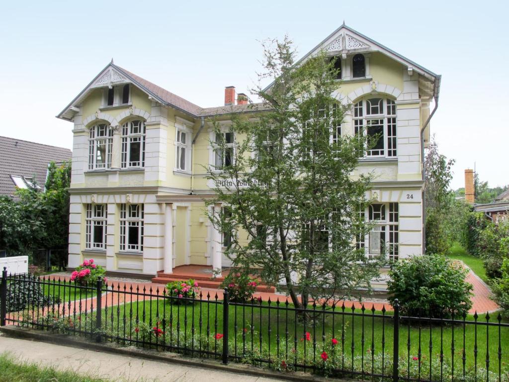 a large white house with a black fence at Apartment Wildrose by Interhome in Zempin