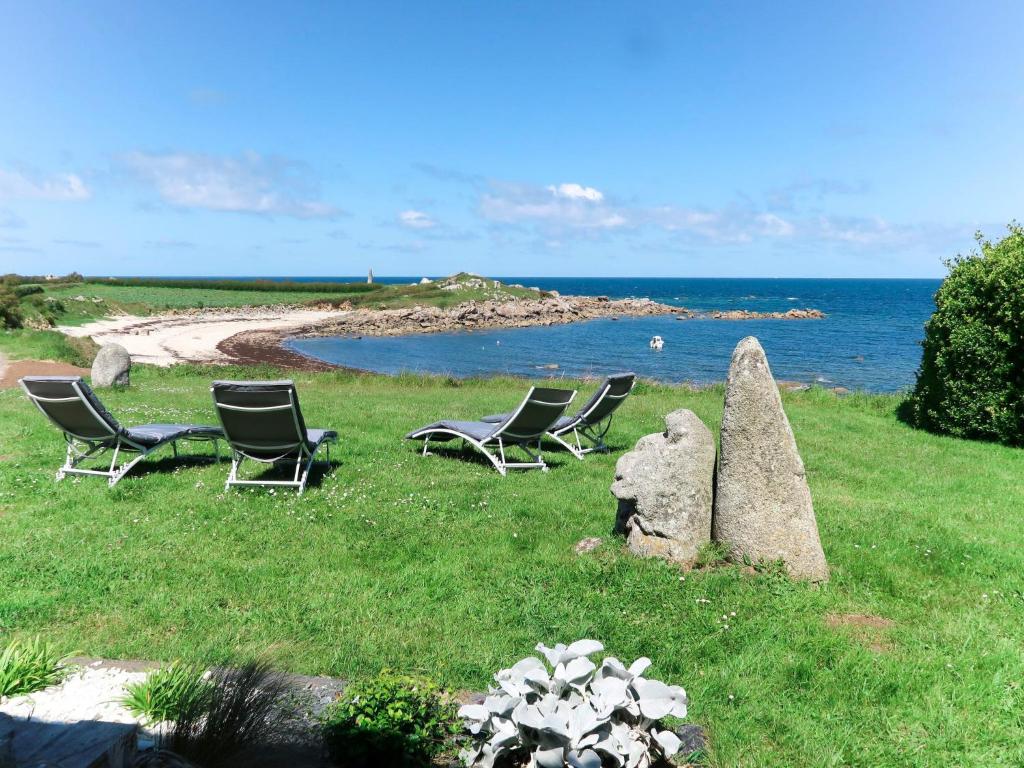 a group of chairs sitting in the grass near the ocean at Holiday Home Cam Louis by Interhome in Plouescat