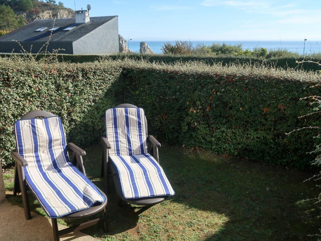 two chairs sitting in the grass next to a hedge at Apartment Fakarava - CZN143 by Interhome in Crozon
