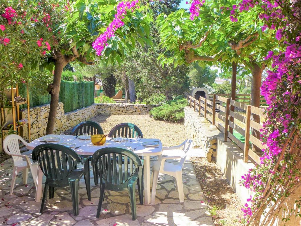 een tafel en stoelen in een tuin met paarse bloemen bij Holiday Home Les Romarines-6 by Interhome in Gruissan