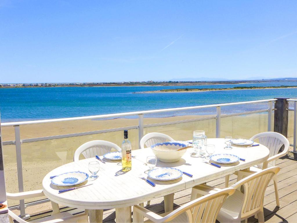 - une table et des chaises blanches sur un balcon donnant sur la plage dans l'établissement Apartment Laguna Beach by Interhome, à Gruissan