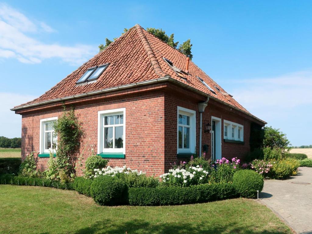 a small brick house with flowers in front of it at Apartment Huuske am Polder by Interhome in Ditzumerhammrich