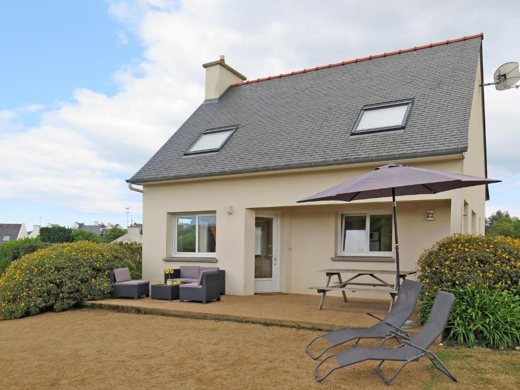 ein Haus mit einem Tisch, Stühlen und einem Sonnenschirm in der Unterkunft Holiday Home de la Plage by Interhome in Pleubian