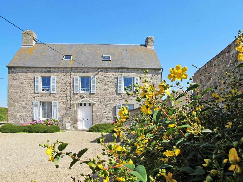 ルヴィルにあるHoliday Home La Ferme du Manoir - RVI400 by Interhomeの黄色い花の石造りの家
