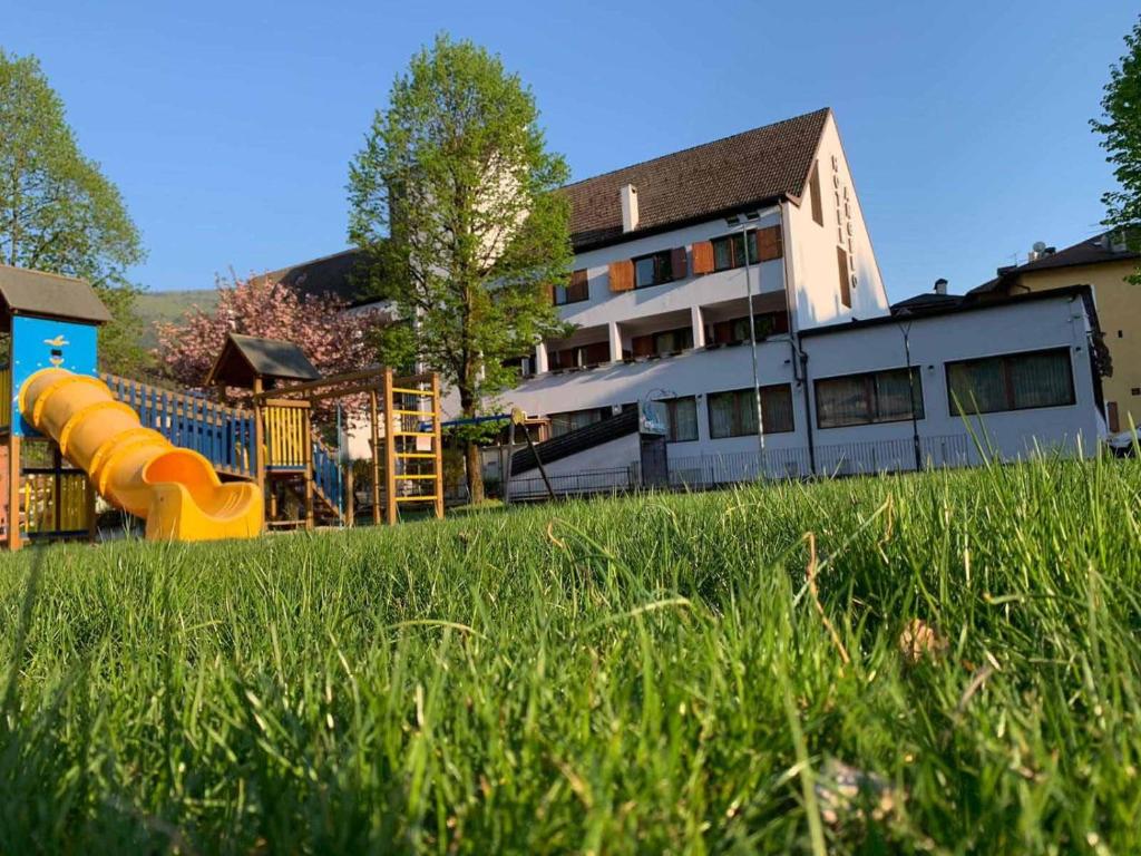 a building with a playground in a field of grass at Hotel Angelo in Comano Terme