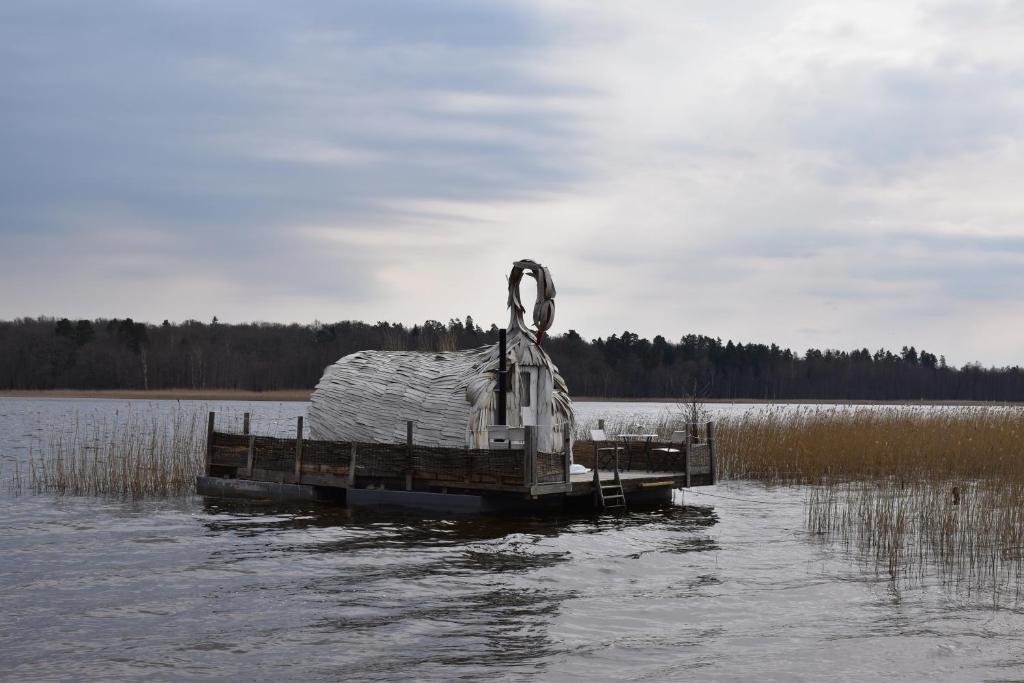 a small dock with a cover on a body of water at Gulbju māja - Swan house in Usma