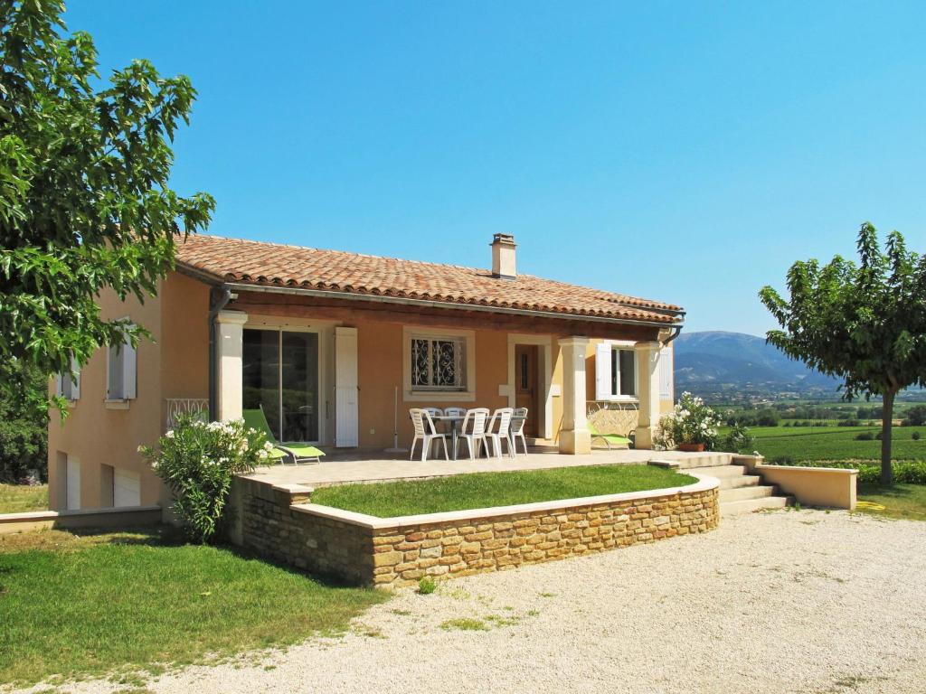 une maison avec une terrasse et des chaises en face de celle-ci dans l'établissement Holiday Home Les Lilas Blancs - VRS205, à Valréas